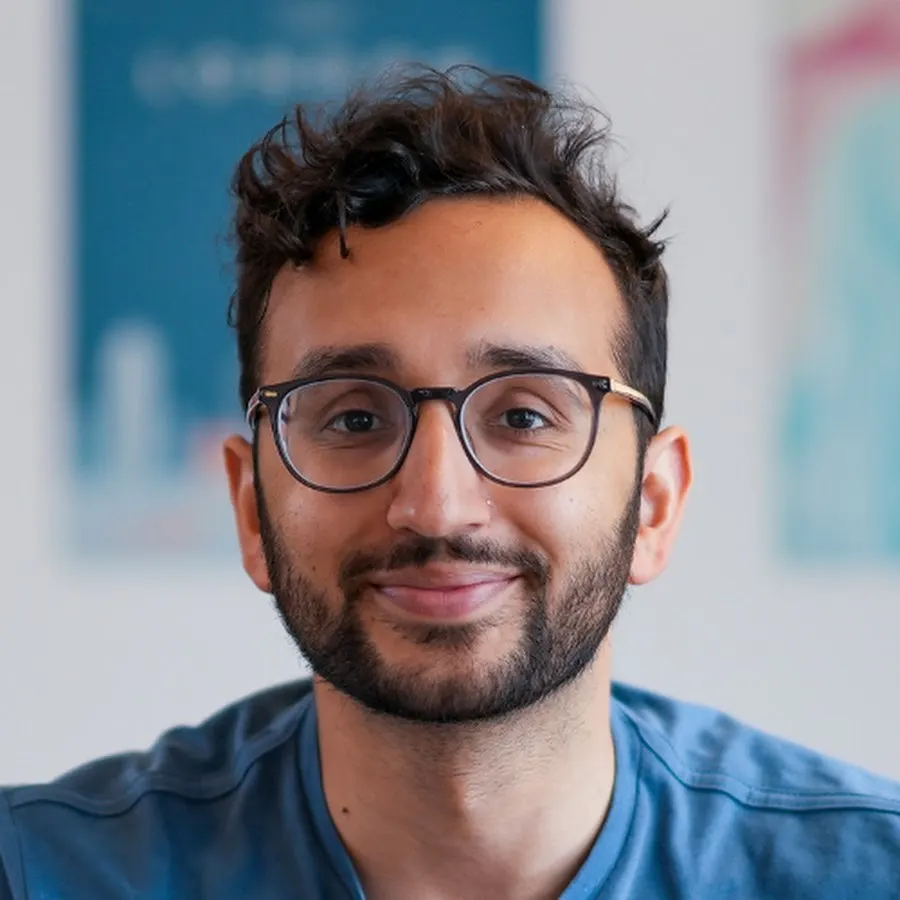 Close portrait of Ali Abdaal in round glasses, smiling
