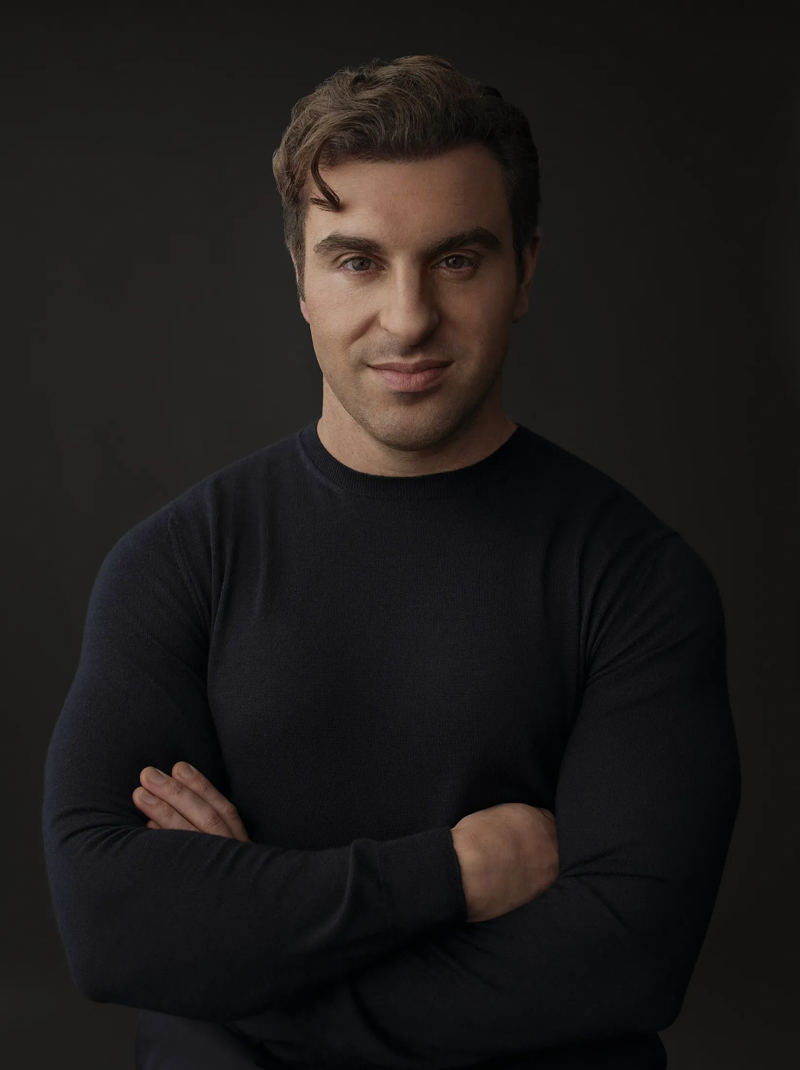Studio portrait of Brian Chesky, arms crossed, dark sweater