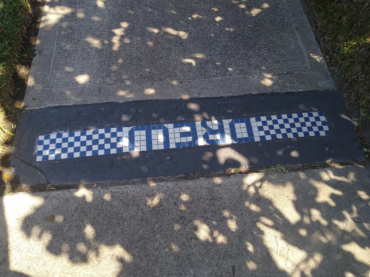 Sidewalk mosaic spelling DROPBOX in blue and white tile
