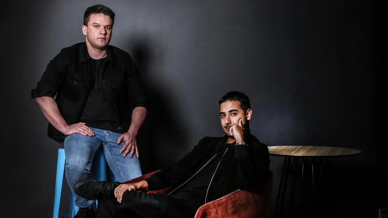 Studio duo portrait, Craven standing beside seated Tehrani