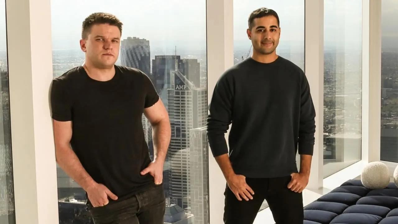 Craven and Tehrani in a Melbourne high-rise with AMP tower visible through the glass
