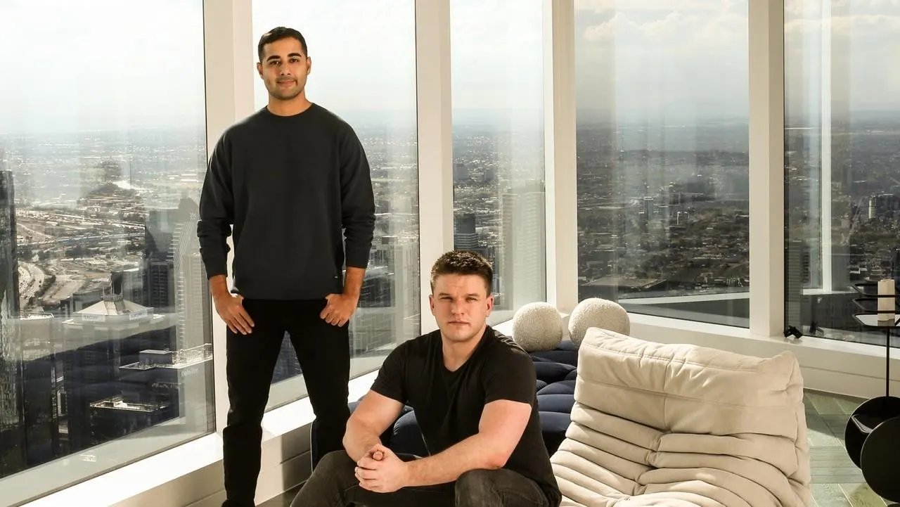 Tehrani standing and Craven seated in high-rise living room