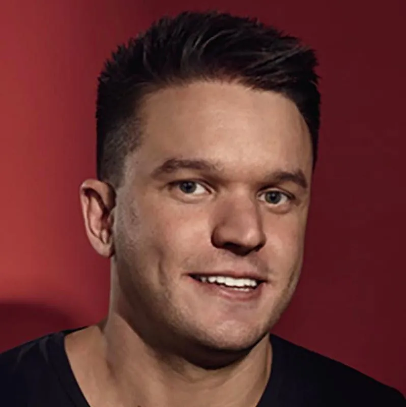 Ed Craven studio headshot on deep red background, black crew neck