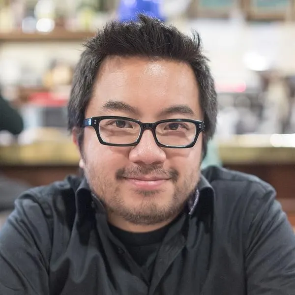 Close color headshot of Garry Tan in black shirt, cafe-like bokeh background