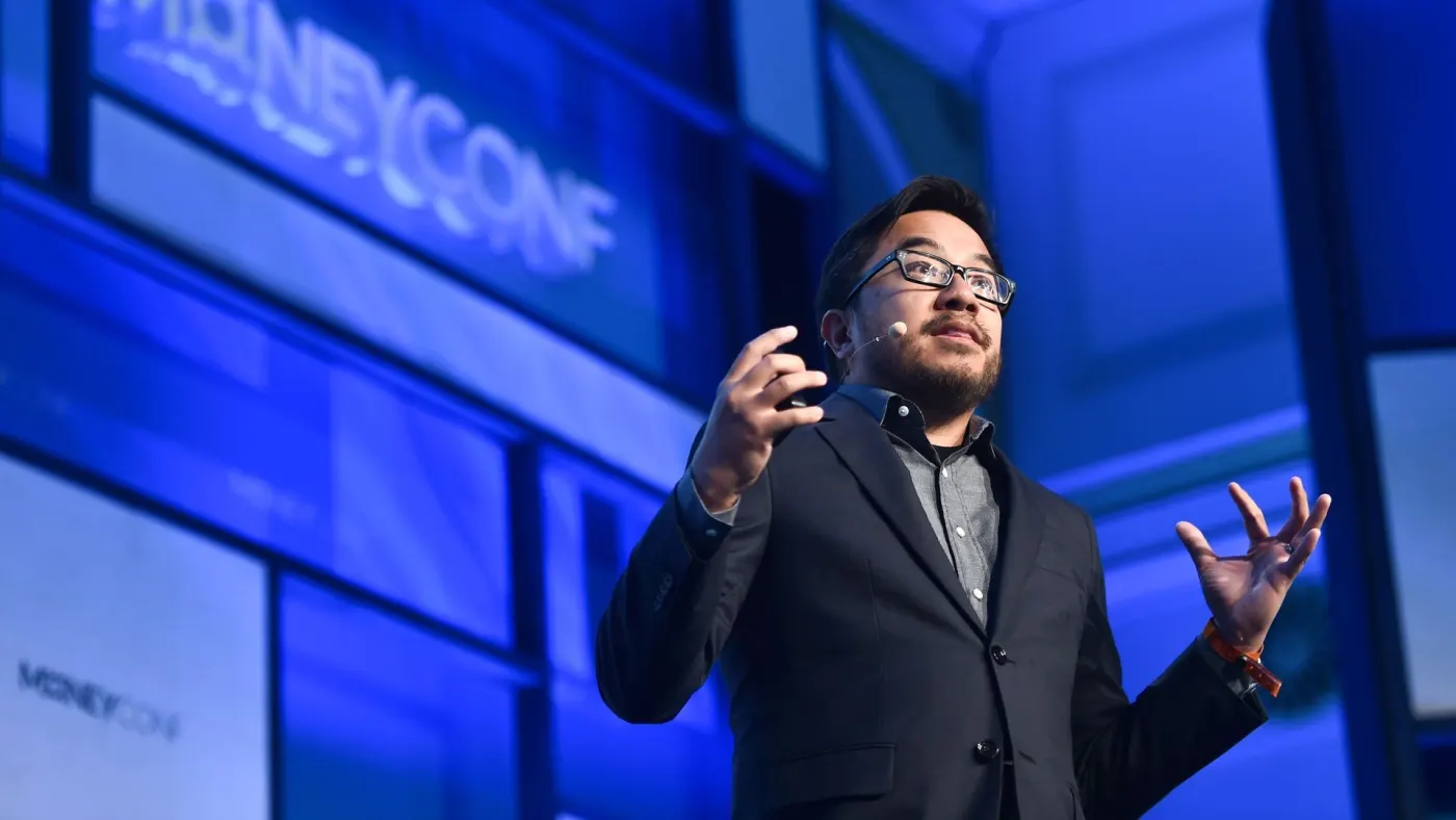 Garry Tan gesturing on blue MONEYCONF stage screens