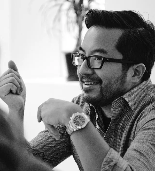 Black-and-white candid of Garry Tan gesturing mid-conversation, watch visible