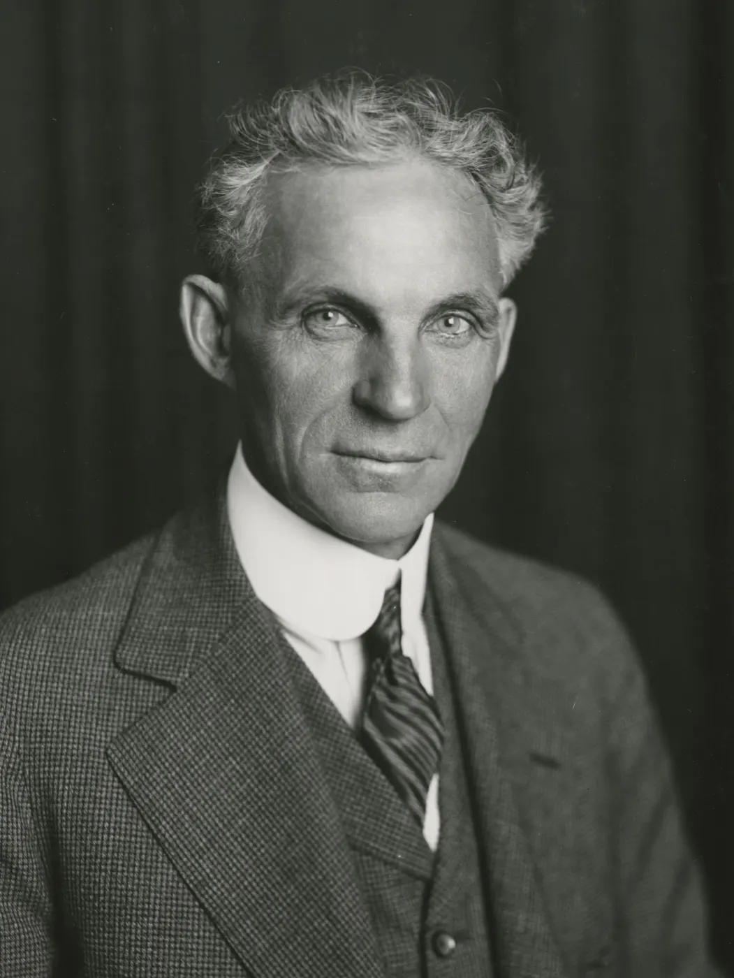 Ford in a dark tweed suit against a dark background