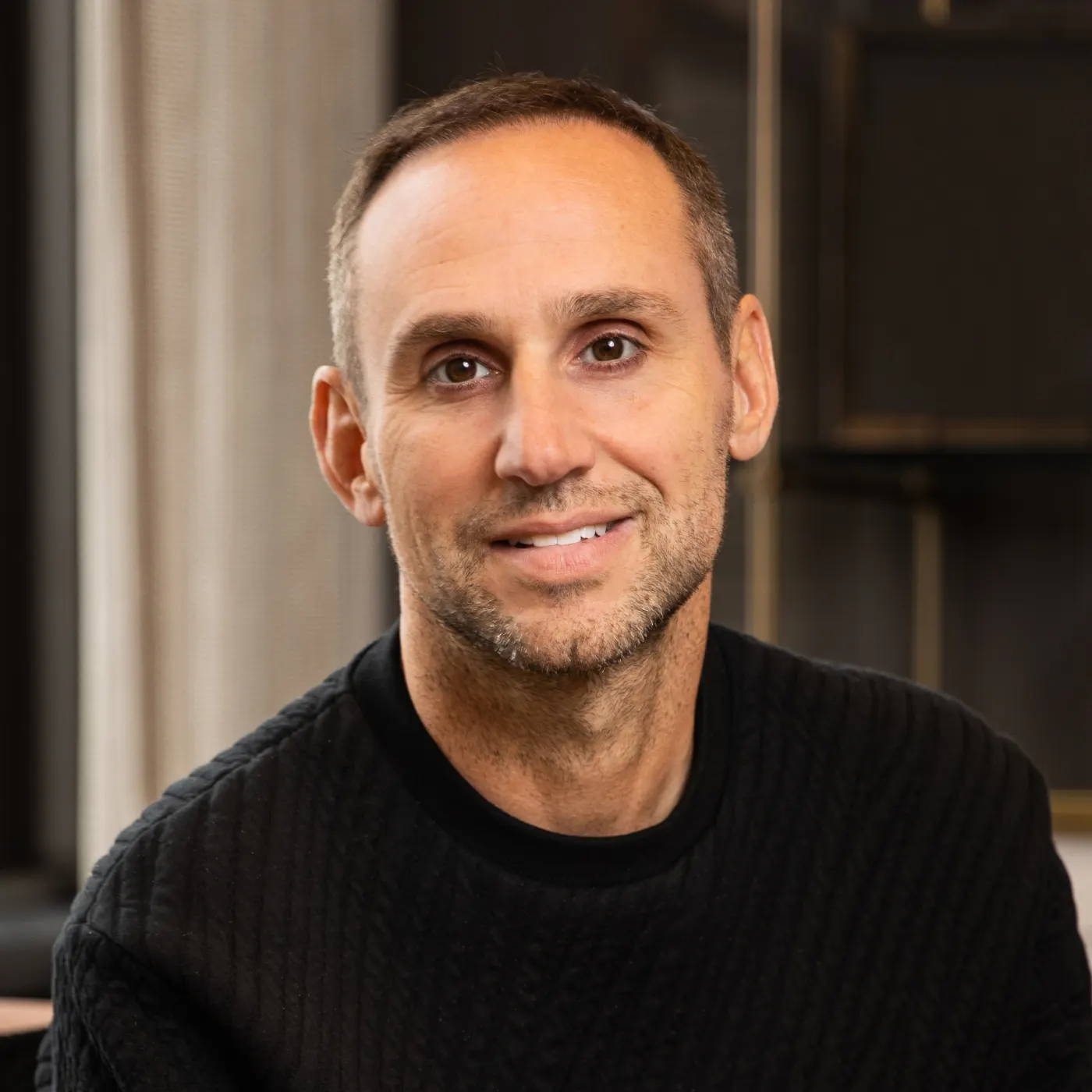 Michael Rubin headshot in black textured sweater, soft indoor light