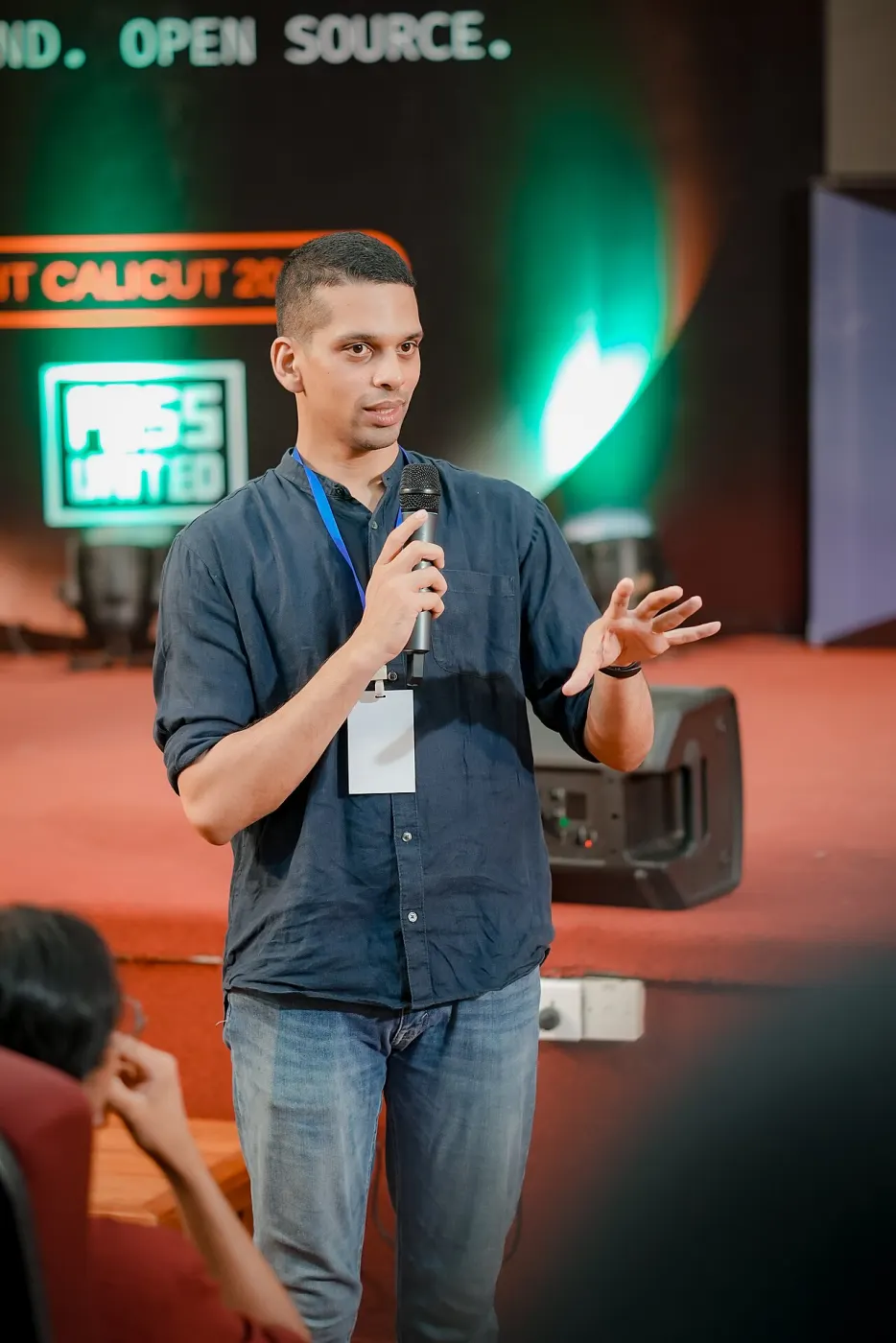 Nithin on stage at FOSS United NIT Calicut with mic and badge