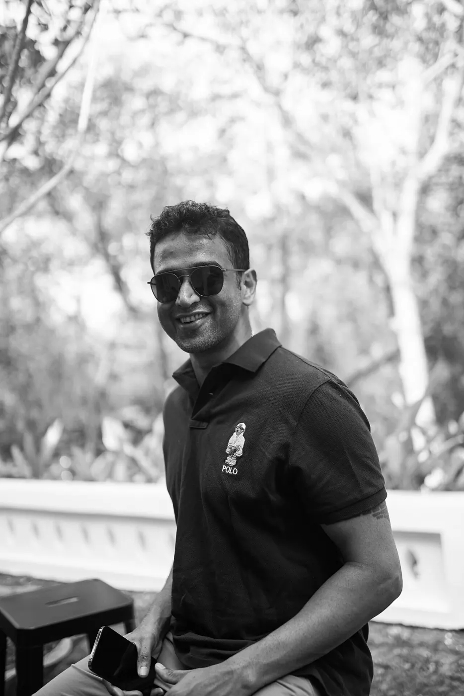 Black-and-white outdoor portrait of Nithin Kamath smiling in sunglasses