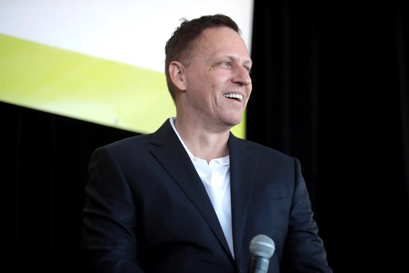 Peter Thiel smiling on stage with microphone