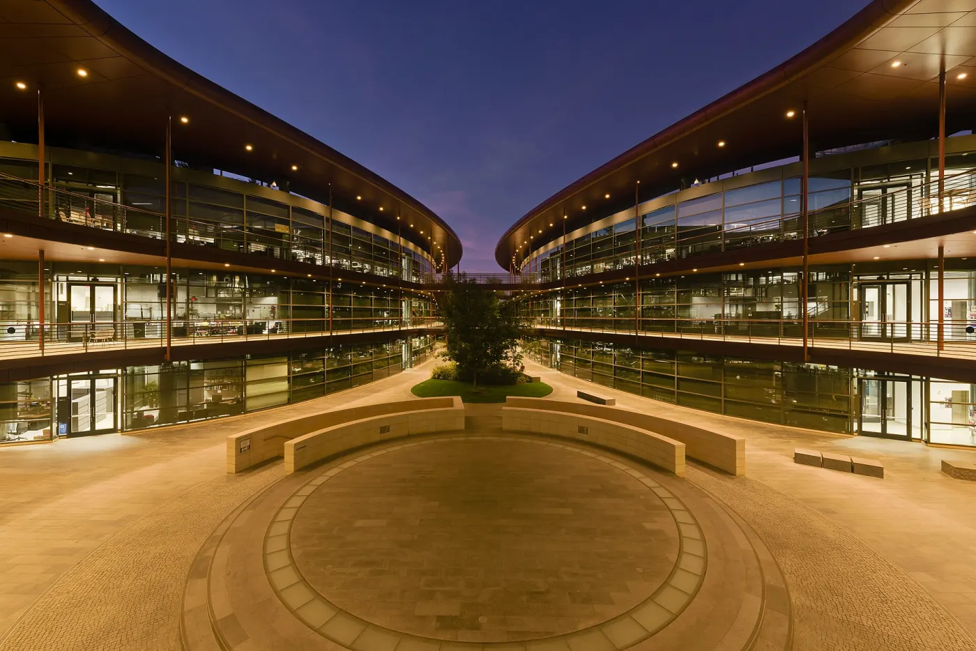 Curved glass campus courtyard at dusk