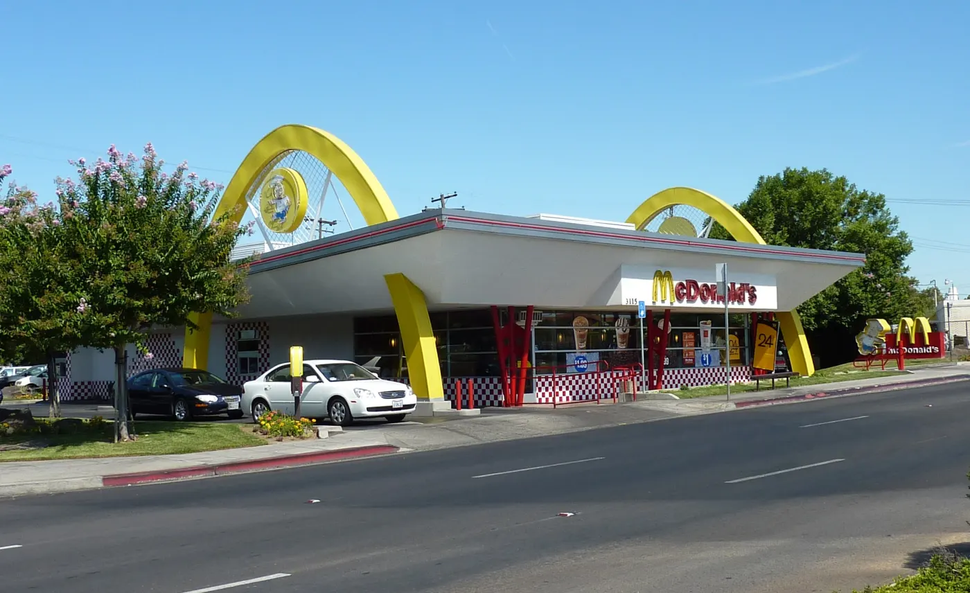 A modern McDonald's with retro golden arches on a sunny street