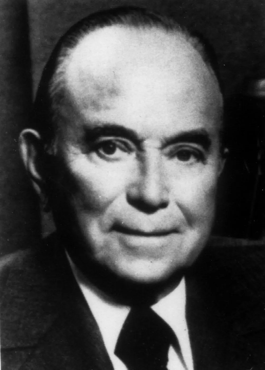Black-and-white studio portrait of Ray Kroc in a dark suit and tie