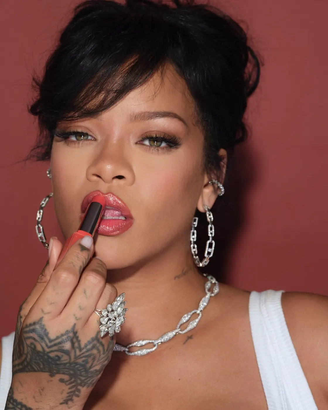 Close shot applying lipstick, hoop earrings, chain necklace
