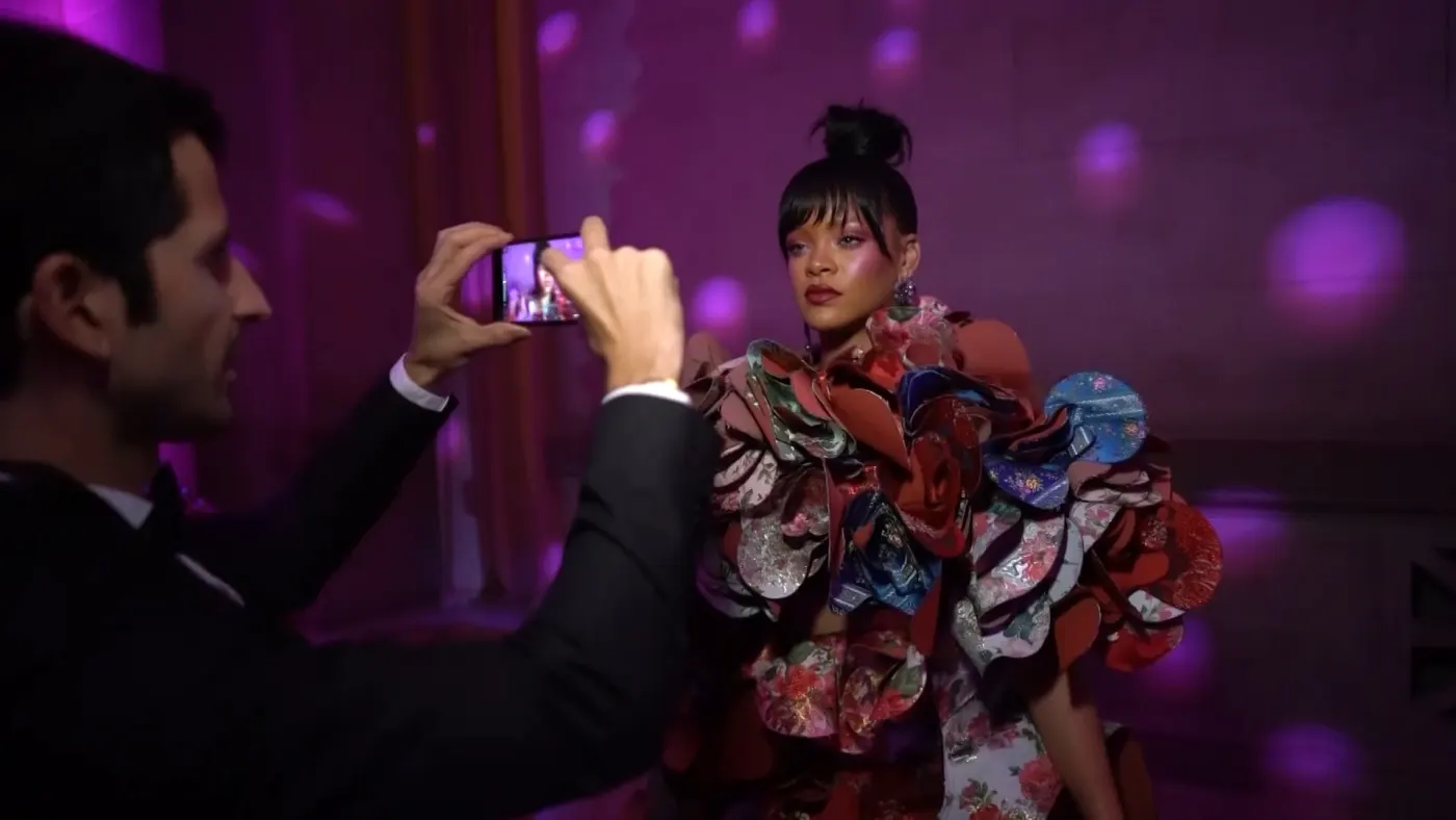 Floral ruffled gown, photographer lifting a phone beside her