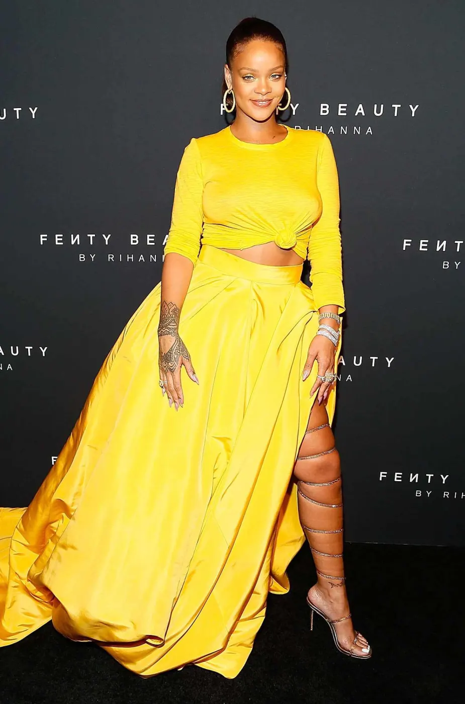 Full-length yellow two-piece gown at Fenty Beauty event wall