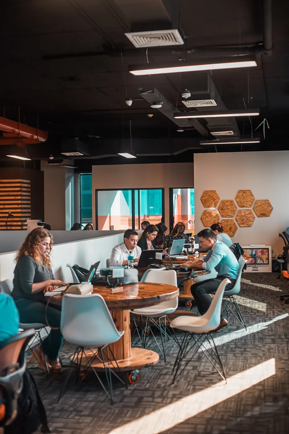 Open coworking floor with spool tables and laptops