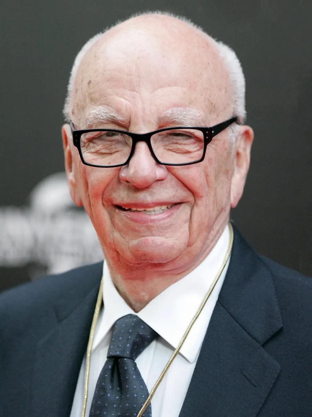 Smiling portrait, black-rimmed glasses, dark suit