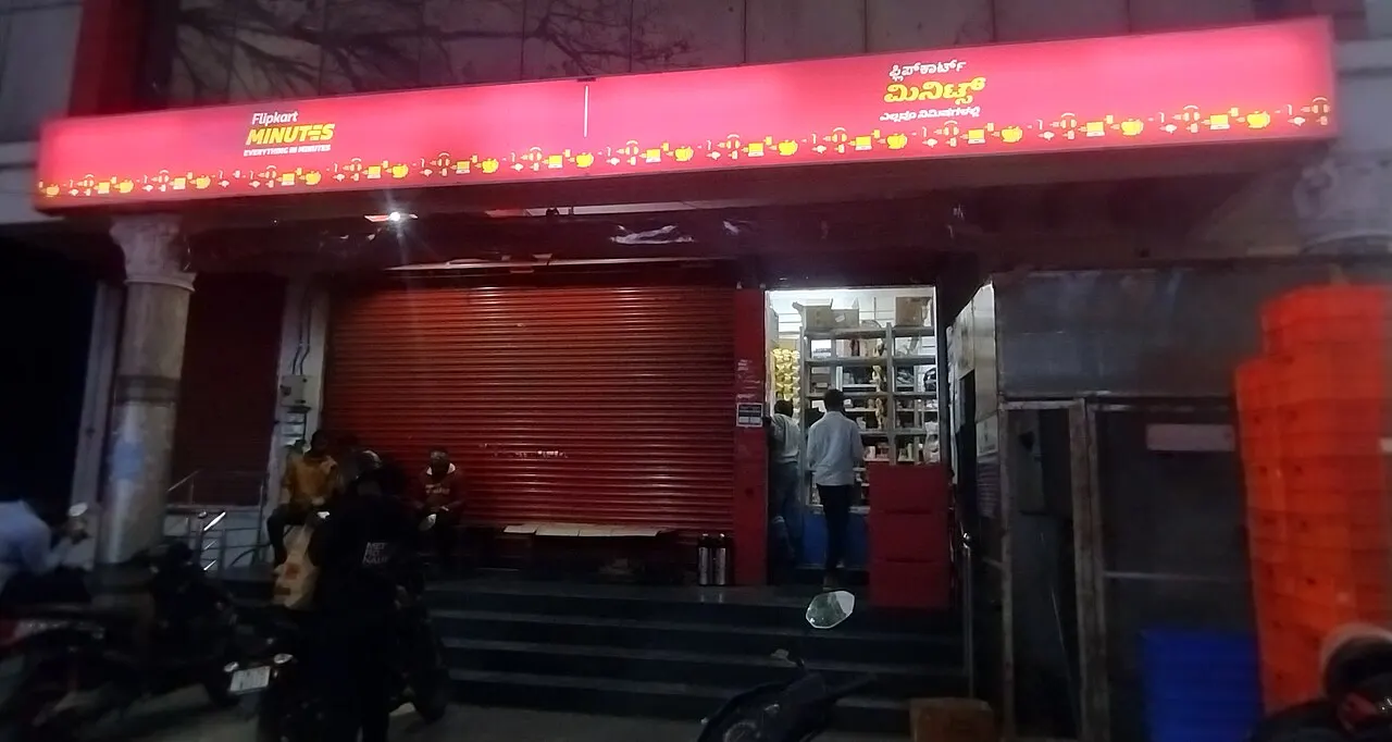 Night storefront of Flipkart Minutes with Kannada and English signage