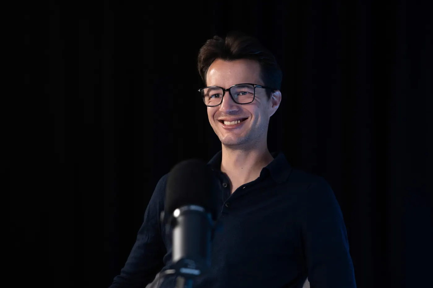 Hacker speaking into a podcast microphone in a dark studio