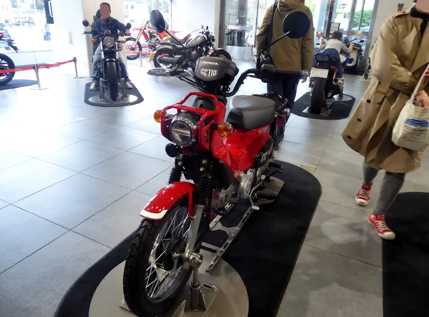 A red vintage Honda motorcycle on display in a museum showroom
