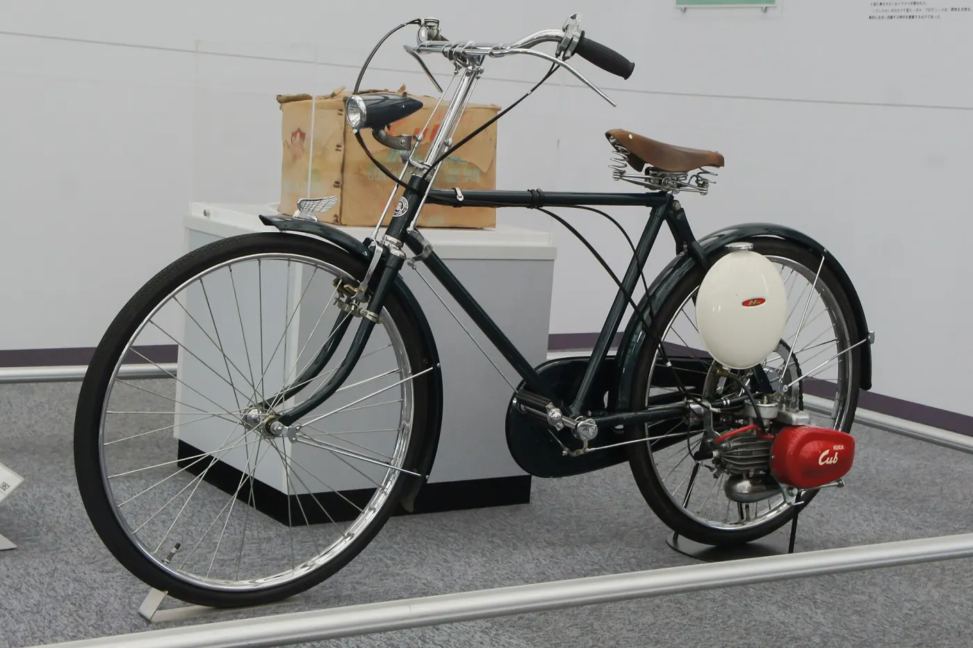 An early Honda motorized bicycle with a small red engine, on display