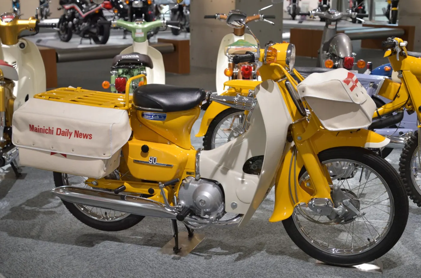 A yellow Honda Super Cub delivery bike with a front basket