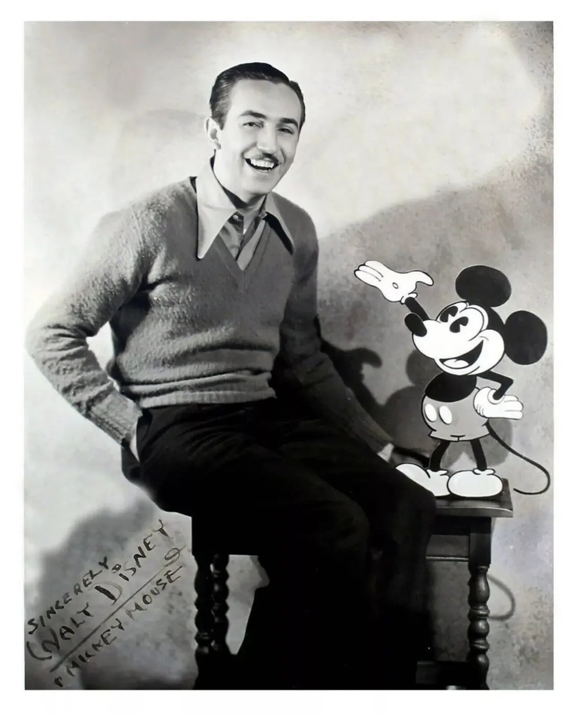 Walt seated beside a Mickey figure, 1929
