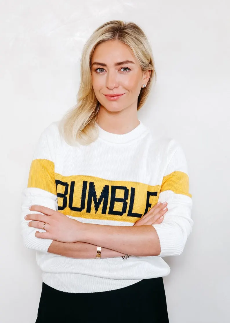 Wearing a white BUMBLE sweater, arms crossed