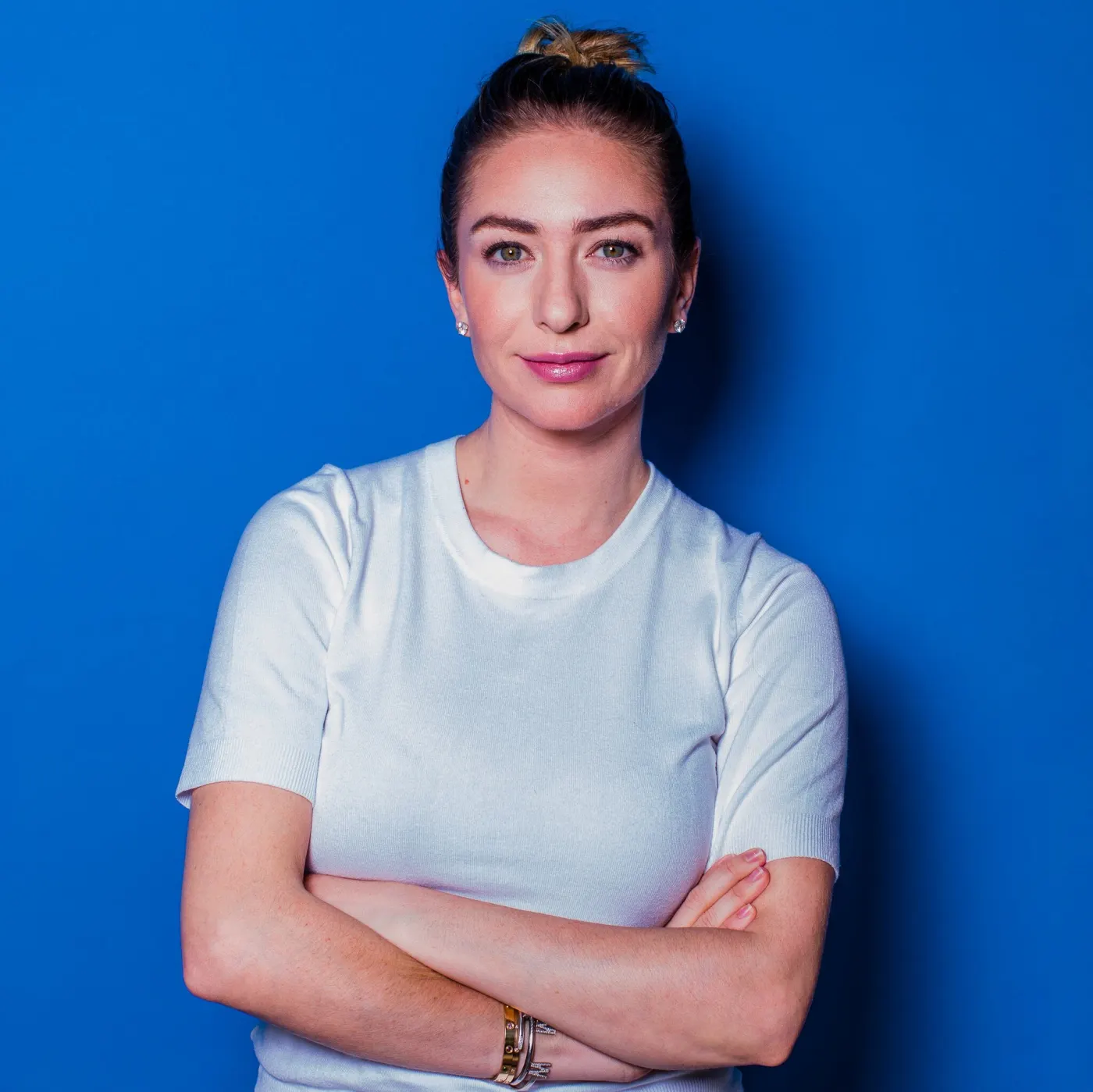 Arms-crossed portrait against a blue backdrop